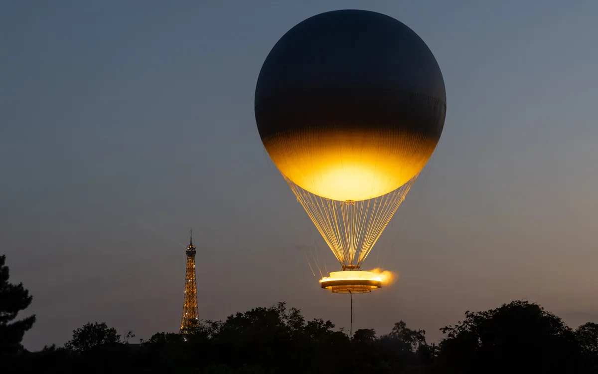 La Vasque de Paris 2024 illuminée au crépuscule, avec la tour Eiffel à l’arrière-plan.